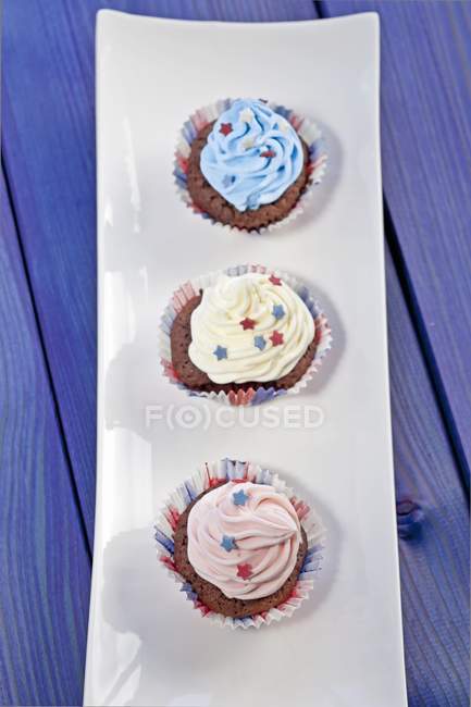 Chocolate cupcakes cobertos com creme colorido — Fotografia de Stock