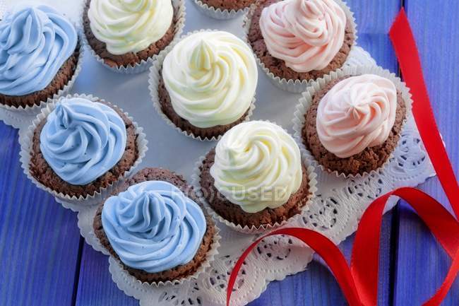 Chocolate cupcakes topped with coloured cream — Stock Photo