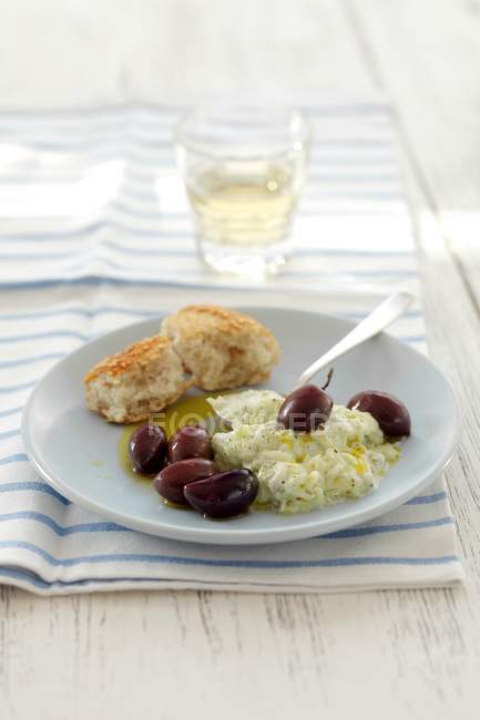 Tzatziki with kalamata olives on plate over towel — Stock Photo