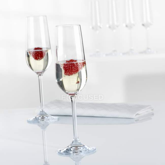 Champagne et framboises dans des verres — Photo de stock