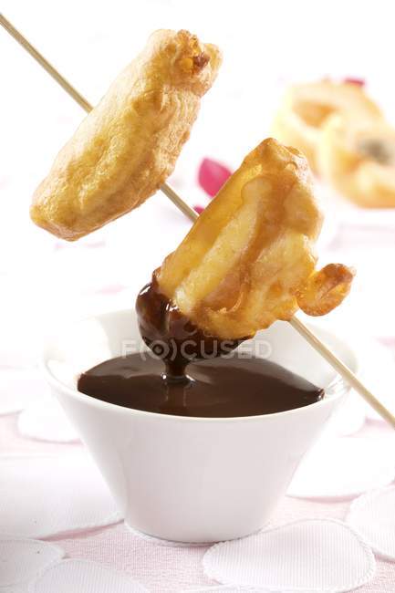 Closeup view of chocolate fondue with battered fruit — Stock Photo