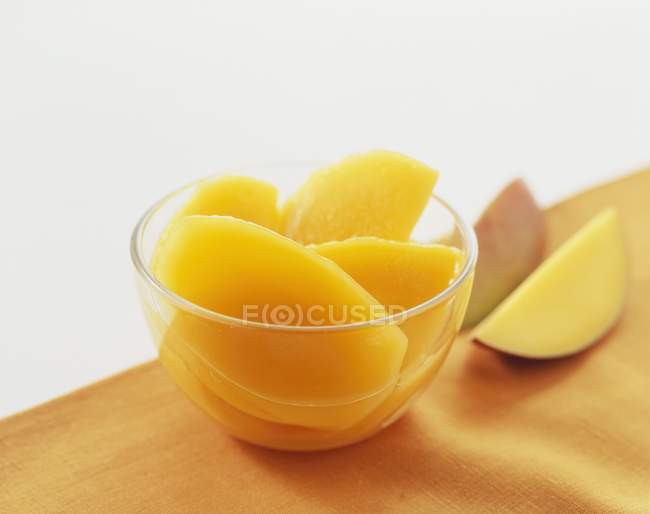 Slices of canned mango in bowl — Stock Photo