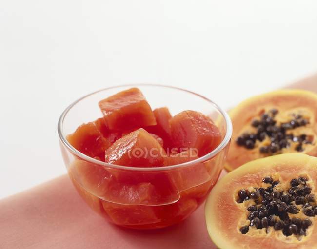 Primo piano vista di pezzi di papaia in scatola in una ciotola e papaia fresca dimezzata — Foto stock
