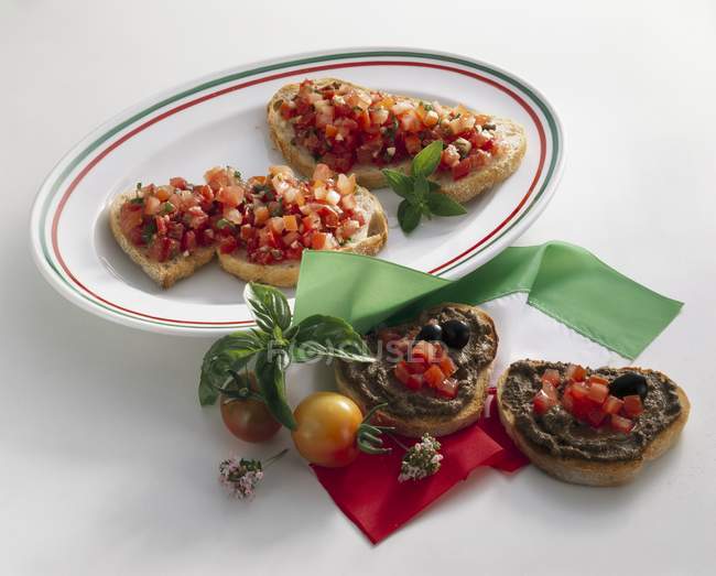 Кростини с помидорами и оливковой пастой на белой поверхности — стоковое фото