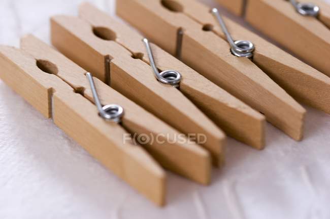 Closeup view of wooden clothes pegs on white surface — Stock Photo
