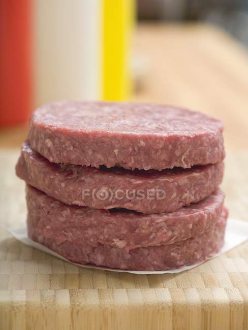 Raw burgers in pile on paper — Stock Photo