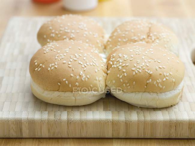 Closeup view of sesame buns for hamburgers on cutting board — Stock Photo