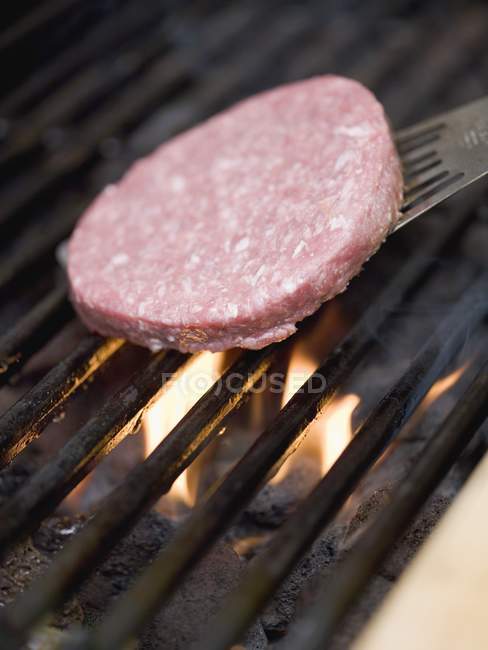 Posizionamento hamburger su rack barbecue — Foto stock
