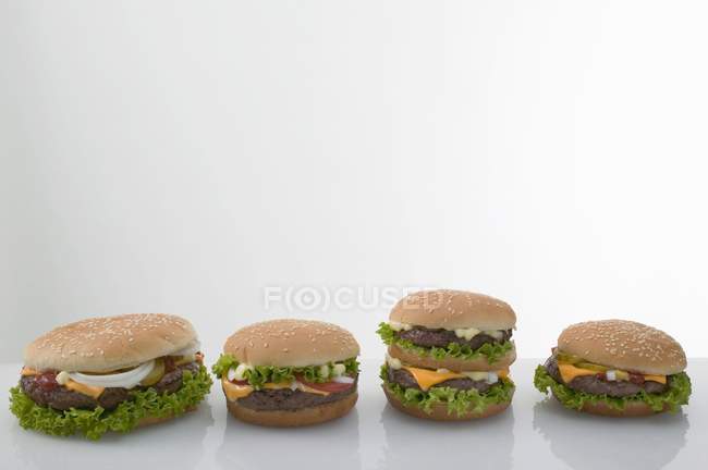 Vier Cheeseburger hintereinander — Stockfoto