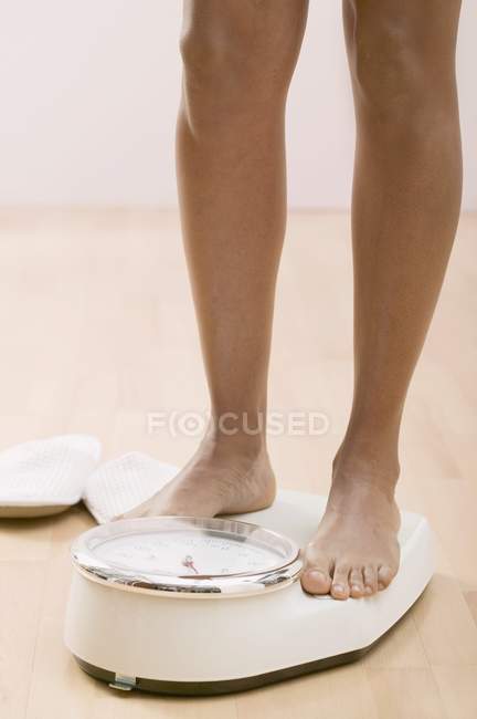 Ausgeschnittene Ansicht weiblicher Beine, die auf Badezimmerwaagen stehen — Stockfoto