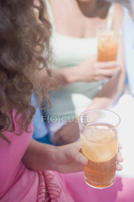 Deux femmes tenant des verres de thé glacé avec des tranches de citron — Photo de stock