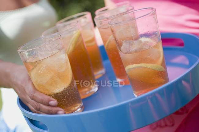 Closeup view of woman taking glass of iced tea from tray — Stock Photo