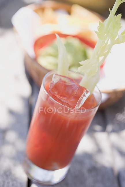 Bebida de tomate com aipo e cubos de gelo em vidro — Fotografia de Stock