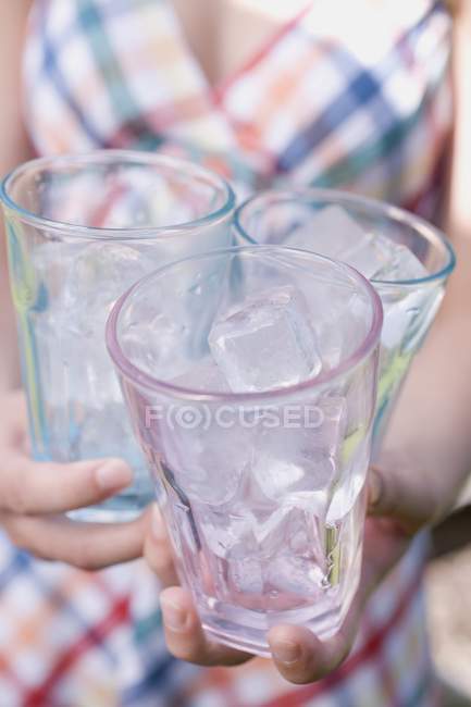Nahaufnahme einer Frau, die drei Gläser mit Eiswürfeln hält — Stockfoto