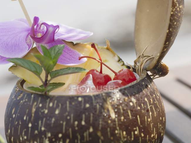 Coco abierto con menta y orquídea - foto de stock