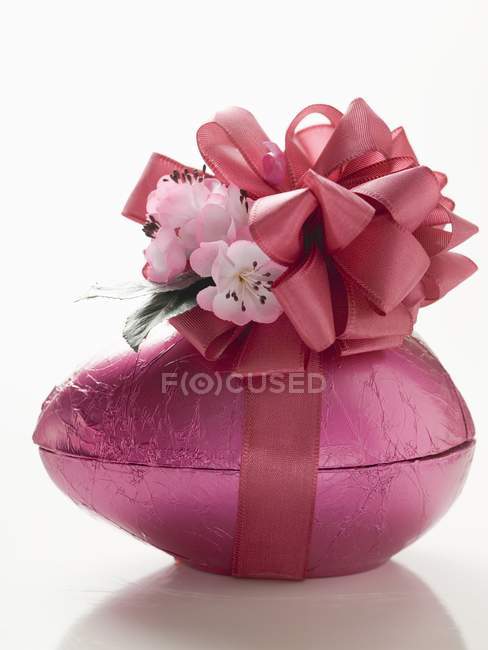 Vista de primer plano de huevo de Pascua de chocolate rosa con arco - foto de stock