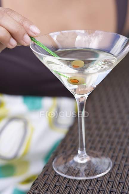 Женщина с зеленой оливкой в стакане мартини — стоковое фото