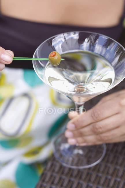 Mulher segurando azeitona verde em vidro Martini — Fotografia de Stock