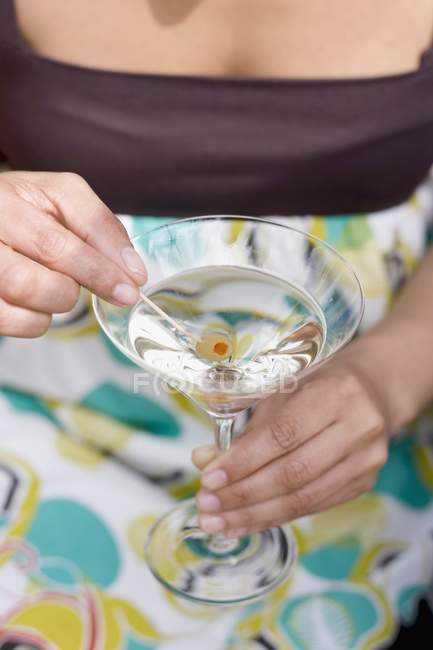Mulher segurando azeitona verde em vidro Martini — Fotografia de Stock