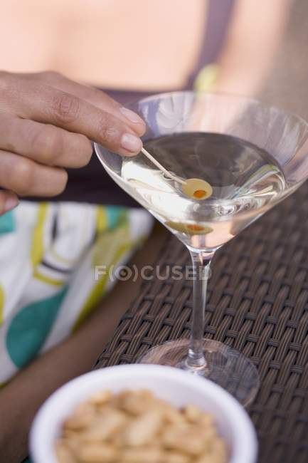 Woman holding green olive in Martini glass — Stock Photo