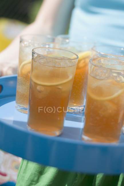 Крупный план обрезанный вид человека, подающего несколько стаканов чая со льдом на подносе — стоковое фото
