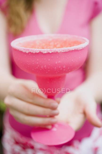 Крупный план женщины, держащей розовый коктейльный бокал с сахарным ободом — стоковое фото