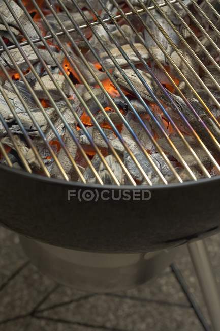 Vue rapprochée des charbons rougeoyants sous la grille de barbecue — Photo de stock