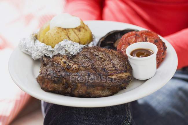 Assiette de steak dans les mains — Photo de stock