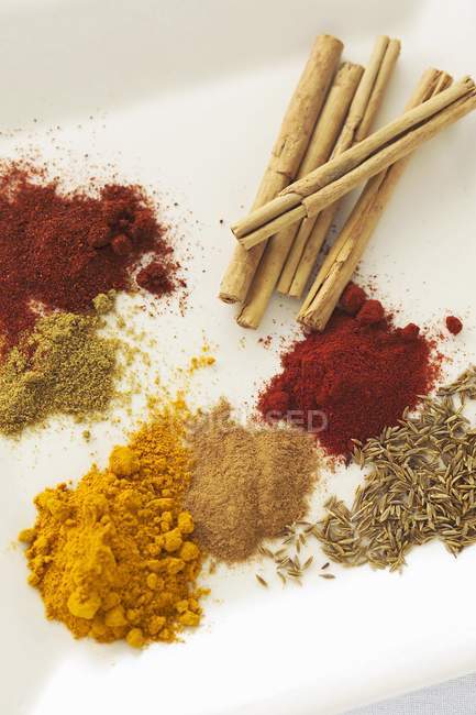Closeup view of various spices heaps on white surface — Stock Photo