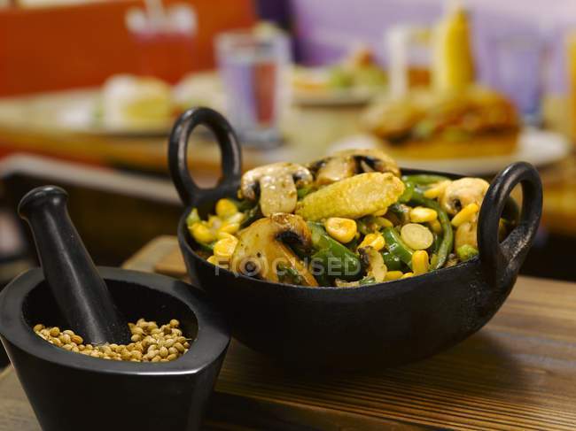 Stir-fried mushrooms, sweetcorn and beans in a small pan over wooden surface — Stock Photo