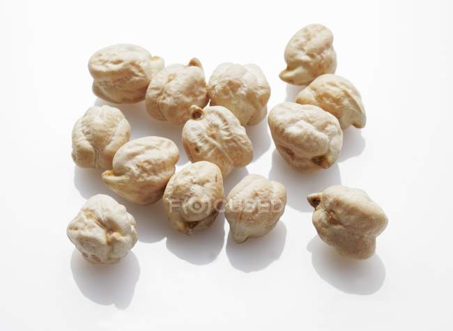 Several dried chick-peas on white surface — Stock Photo