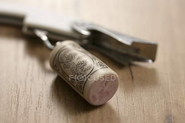 Closeup view of one corkscrew with cork on wooden background — Stock Photo