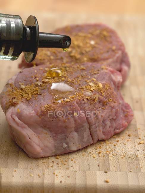Polvilhando medalhões de carne temperada com óleo — Fotografia de Stock