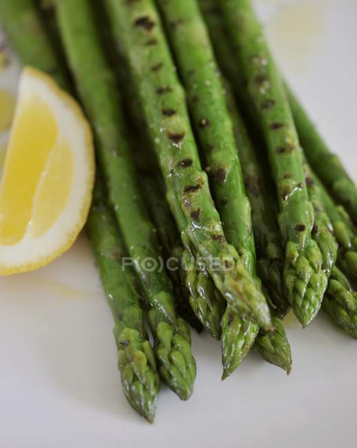 Green asparagus with lemon slice — Stock Photo