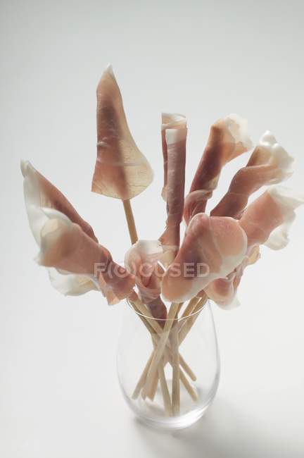 Grissini wrapped in raw ham in glass — Stock Photo