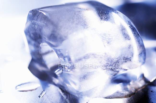 Крупный план одного тающего кубика льда на металлической поверхности — стоковое фото