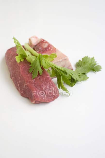 Шматок сирої яловичини з кісткою і петрушкою — стокове фото