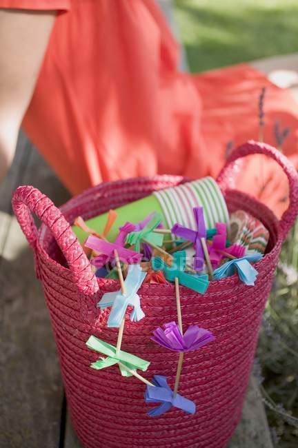 Vista diurna de colorida cesta de decoraciones para una fiesta en el jardín con la mujer en el fondo - foto de stock