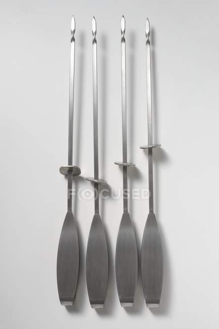 Top view of four barbecue skewers on white surface — Stock Photo
