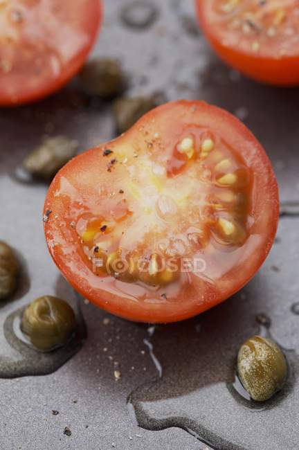 Tomates cherry cortados a la mitad con alcaparras y vinagreta - foto de stock