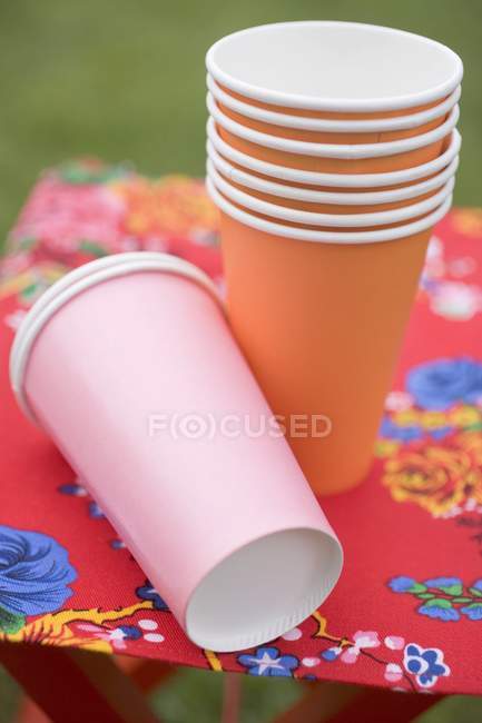 Tasses et assiettes en papier coloré sur tabouret pliant — Photo de stock