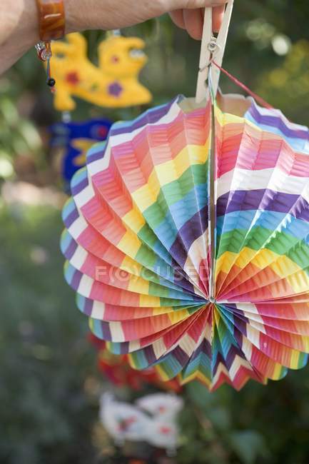 Hand hanging colored Chinese lantern on washing line in garden — Stock Photo