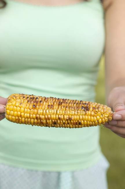 Женщина держит жареную кукурузу — стоковое фото