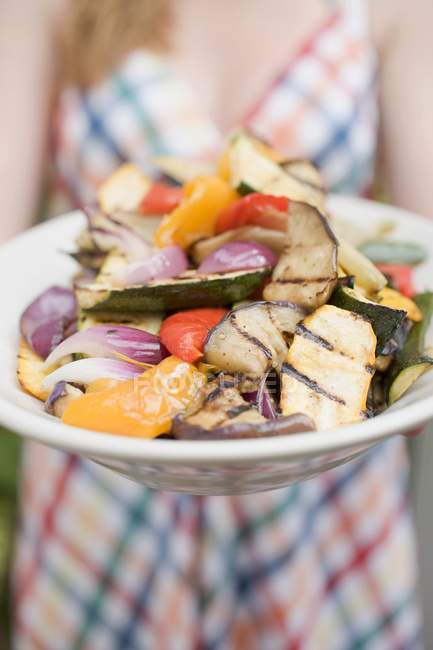 Woman holding a plate of grilled vegetables in hand — Stock Photo