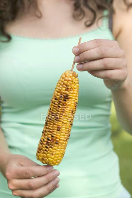Mujer sosteniendo maíz a la plancha - foto de stock