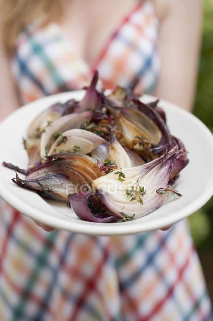 Woman holding a plate of grilled red onions, midsection — Stock Photo