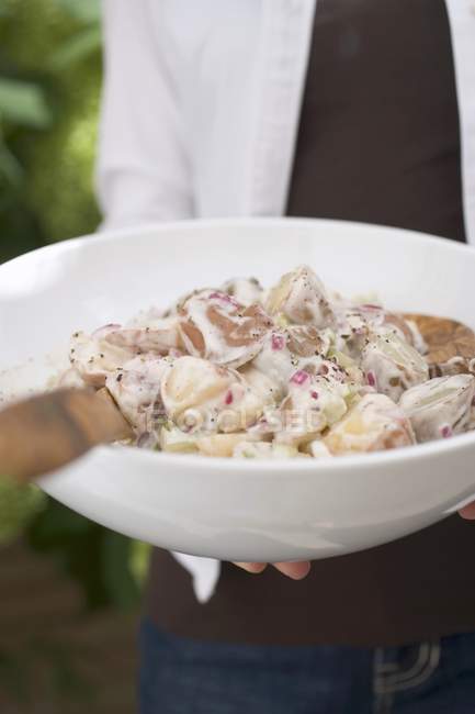 Cropped view of person holding a dish of potato salad in hands — Stock Photo
