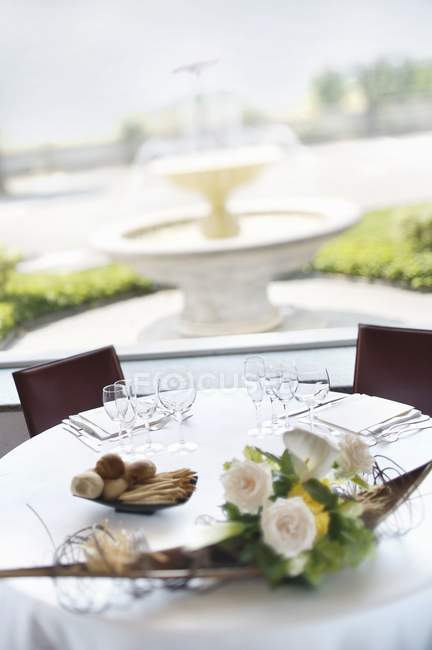 Vista diurna de la mesa de desayuno con aperitivos y flores en una terraza - foto de stock