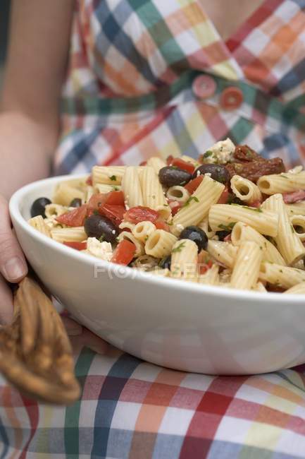Woman holding dish of pasta salad — Stock Photo