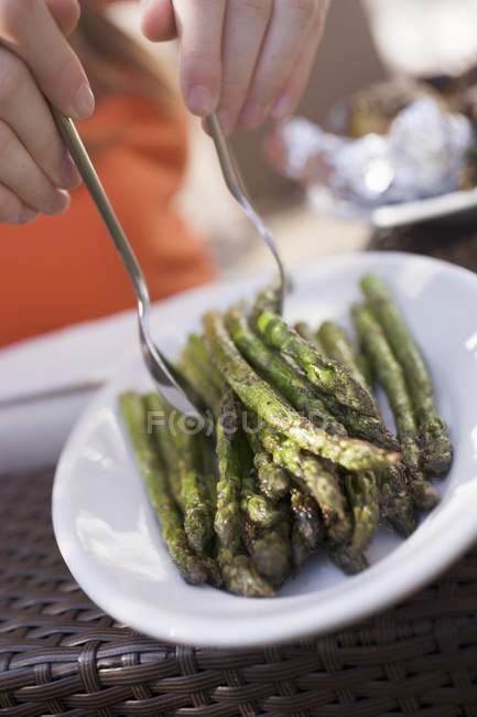 Human hands taking grilled asparagus — Stock Photo